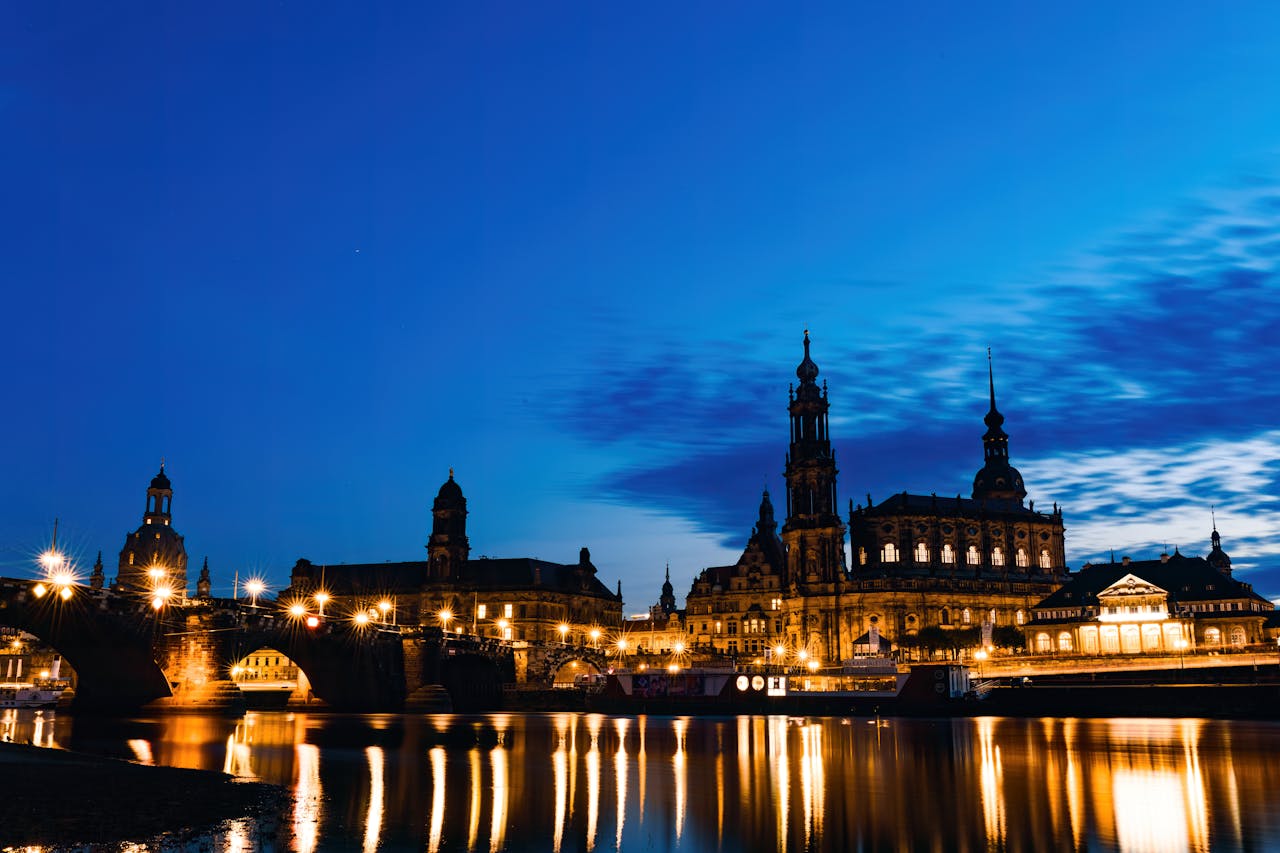 Scenic nighttime view of Dresden's illuminated historical architecture reflecting on the Elbe River.